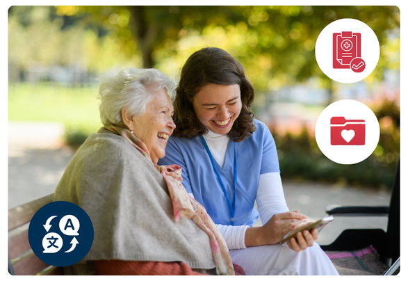 Caregiver in blue scrubs shares a phone with a smiling elderly woman on a park bench outside, she shows her the translated discharge instructions in her own language